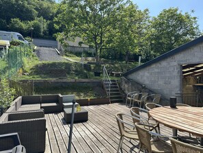Eine Holzterrasse mit Korbmöbeln, einem Tisch und Stühlen.