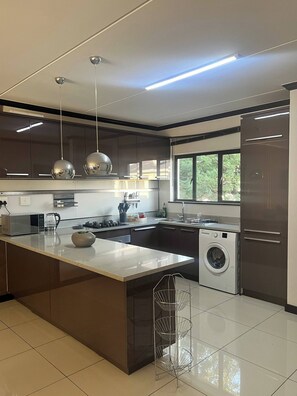 A modern kitchen with a central island, stainless steel appliances, and a built-in washing machine. - Light-filled 2BR 2BA Spacious Apartment (Johannesburg)