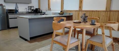 Une cuisine dotée d’un îlot central, de chaises en bois et d’un tapis à motifs.