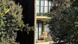 A modern house with a stone facade, large windows, and a wooden balcony. - Idan Barn Suites and Cafè (Naro Moru)