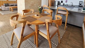 A modern kitchen with a central island, wooden chairs, and a dining table. - Idan Barn Suites and Cafè (Naro Moru)