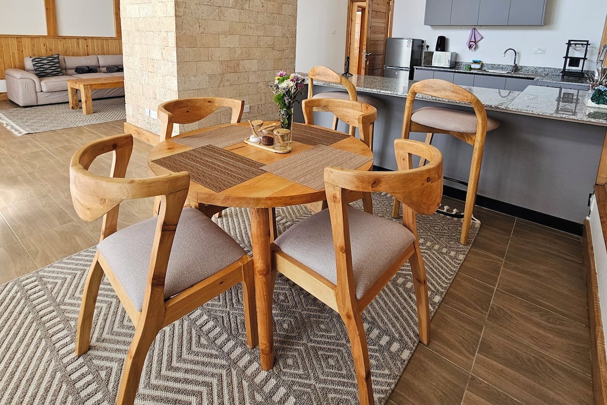 Una cocina moderna con una isla central, sillas de madera y una mesa de comedor.