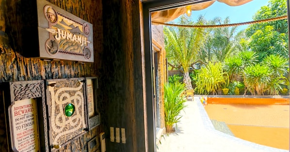 Une pièce décorée sur le thème de la jungle, avec une enseigne « JUMANJI » et une console de jeu « JUMANJI ».