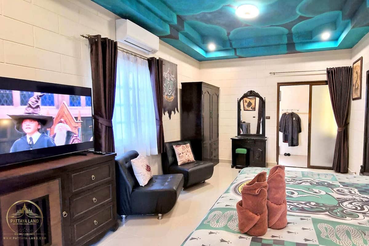 Un dormitorio con televisión, armario, espejo y cama con colcha estampada.