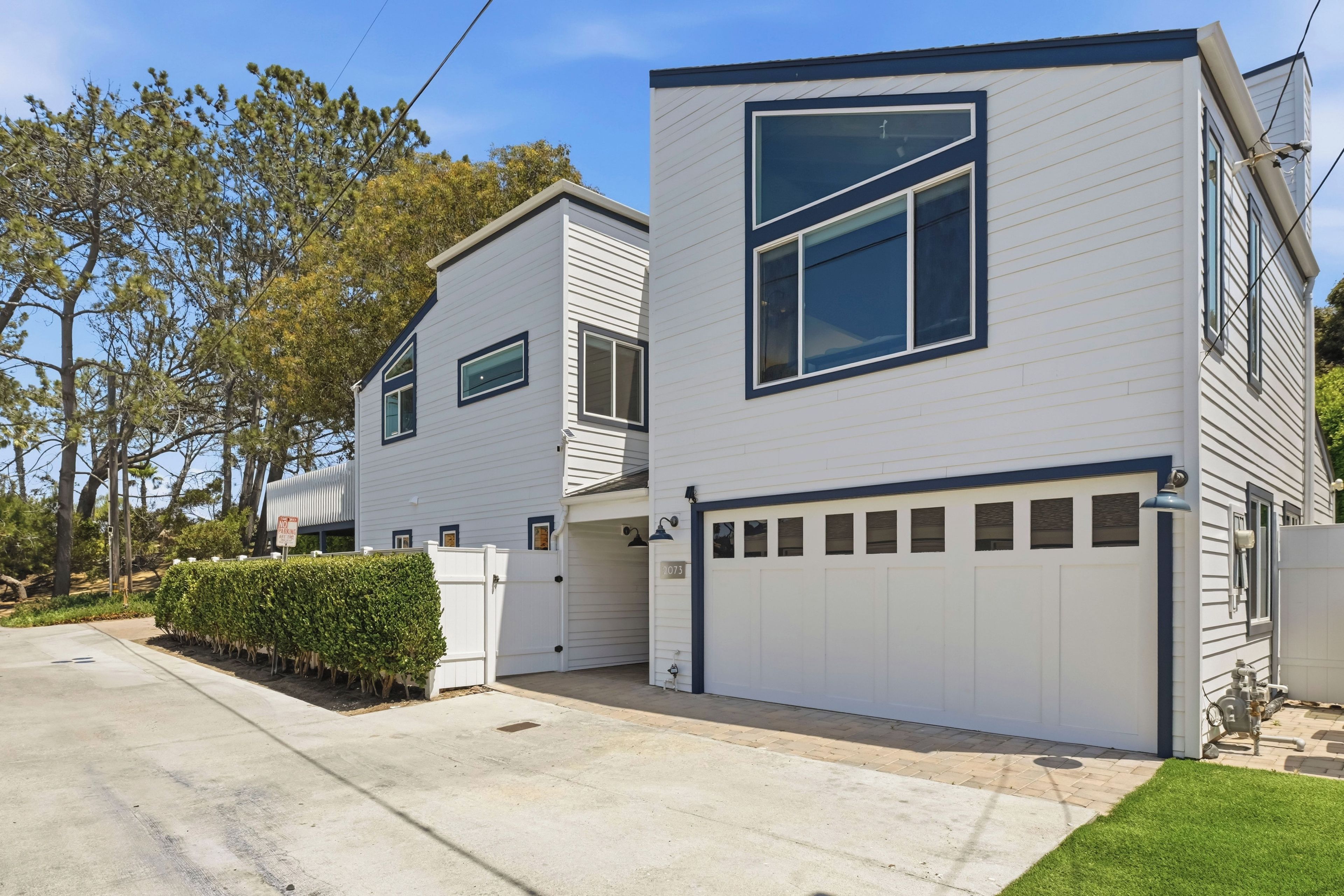 A modern two-story house with a garage, a well-maintained lawn, and a clear sky.