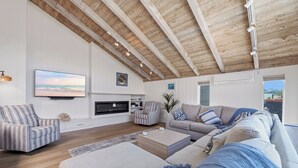A spacious living room with a high ceiling, a fireplace, a large sofa set, and a television mounted on the wall. - Sand and Spa Retreat in Del Mar (Del Mar)