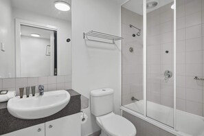 A bathroom with a sink, toilet, and glass-enclosed shower. - City Centre - Little Bourke Street - 1BD Apartment (Melbourne)