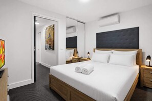 A hotel room with a large bed, two bedside tables, a mirror, and a painting on the wall. - City Centre - Little Bourke Street - 1BD Apartment (Melbourne)