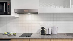 Una cucina moderna con forno a microonde integrato, bollitore, tostapane e macchina del caffè sul piano di lavoro.
