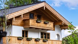 Un chalet in legno con un balcone, ampie finestre e un arco in pietra.