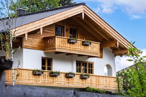Eine Holchhütte mit Balkon, großen Fenstern und einem Steinbogen.