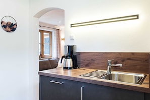 Eine moderne Küche mit Kaffeemaschine, Spüle und einer Holzauszugplatte.