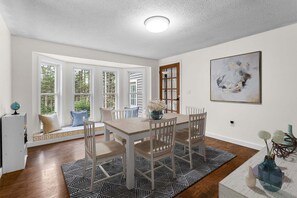 A dining area with a table, chairs, and a view through large windows. - The Bayside Retreat-NEW! (Trenton)