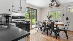 Een moderne keuken met witte kasten, een gasfornuis en een eethoek met een houten tafel en stoelen.