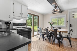 Eine moderne Küche mit weißen Schränken, einem Gasherd und einem Essbereich mit Holztisch und Stühlen.