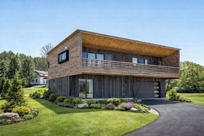 Ein modernes, zweigeschossiges Haus mit Holzfassade, großen Fenstern und einem gepflegten Rasen.