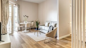 A modern living room with a sofa, a dining table with chairs, a coffee table, and a TV on a stand. - Casa Vostra Vaticano (Rome)