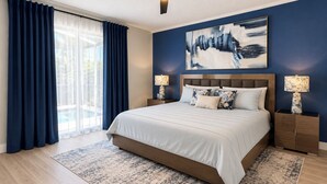 A bedroom with a bed, two bedside tables, a ceiling fan, and a large window with curtains. - Stunning Pool Home With Golf Course Views (Davenport)