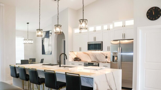 A modern kitchen with a marble island, stainless steel appliances, and pendant lighting. - Stunning Pool Home With Golf Course Views (Davenport)