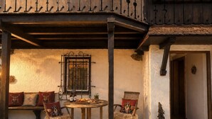 Un área de estar al aire libre de estilo rústico, con una mesa de madera, dos sillas y un banco.