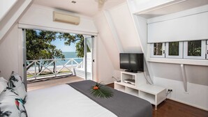 A bedroom with a bed, a TV, and a balcony with a view of the sea. - Cottonwood Port Douglas (Oak Beach)