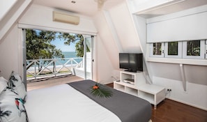 Ein Schlafzimmer mit Bett, Fernseher und einem Balkon mit Meerblick.
