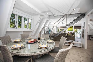Ein Essbereich mit Glastisch, Korbstühlen und einer Treppe.