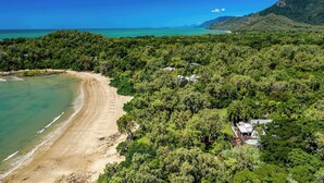 An aerial view of a coastal property with a beach, dense forest, and a house with a pool. - Cottonwood Port Douglas (Oak Beach)