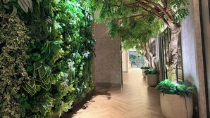 Un pasillo con jardín vertical en una pared, suelo de madera y un ventanal al final.