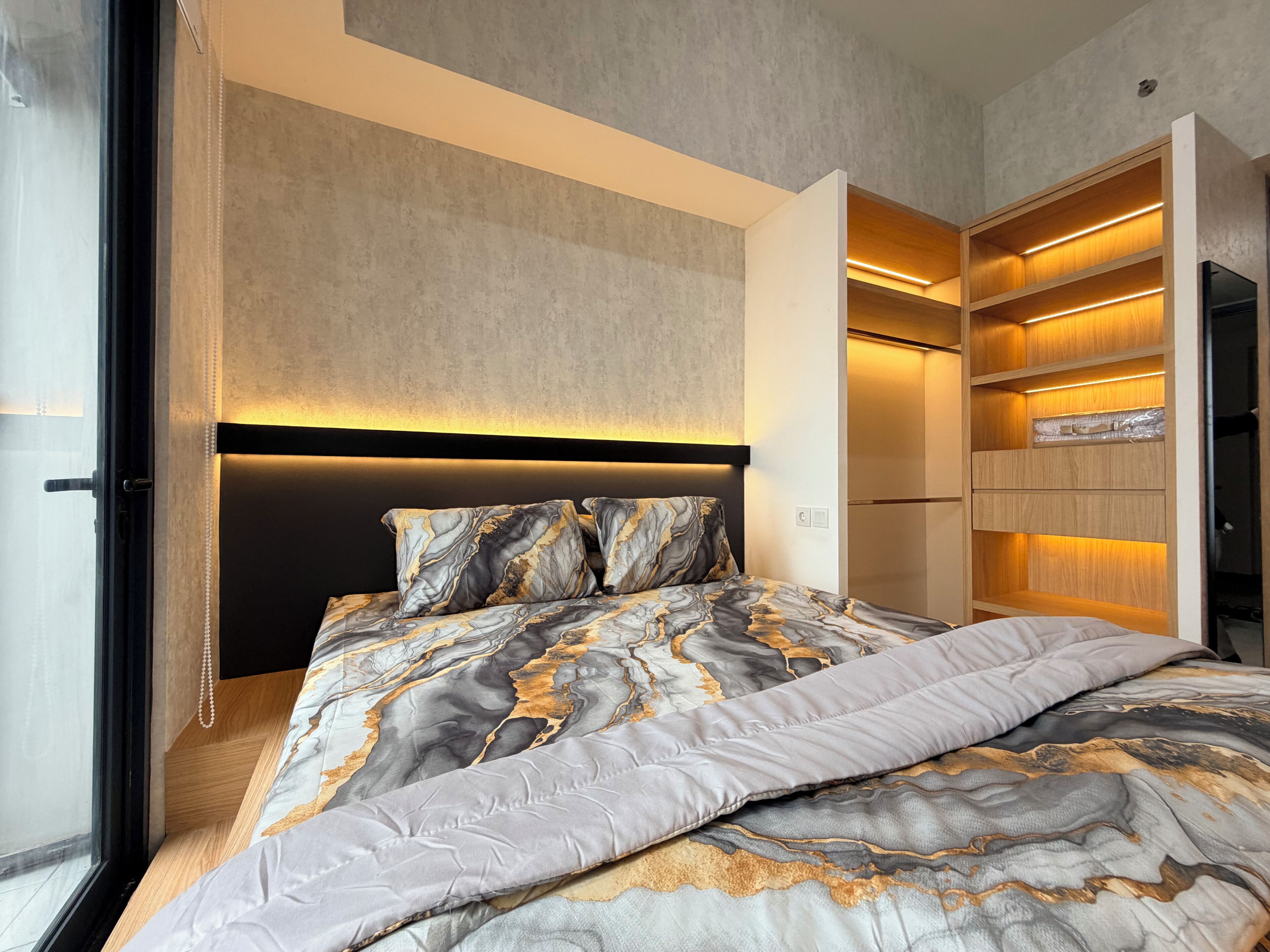 Un dormitorio moderno con cama, estanterías empotradas y cabecera con iluminación integrada.