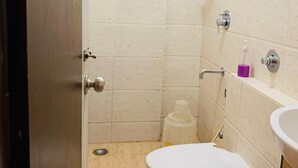 A small bathroom with a toilet, a sink, and a shower. - i residency copital o (Bangalore)