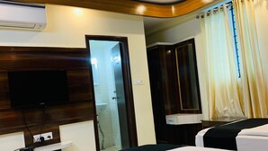 A hotel room with a bed, a TV, an air conditioner, a mirror, and a curtain. - i residency copital o (Bangalore)