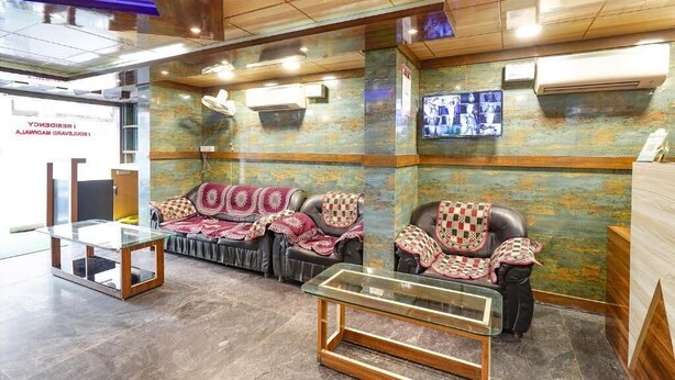 A reception area with a glass desk, two leather sofas with patterned cushions, a wall-mounted TV, and a wooden ceiling. - i residency copital o (Bangalore)