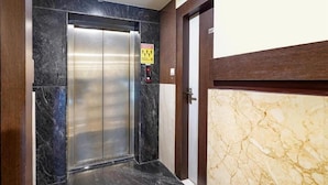 An elevator with a marble wall and a door with a number plate. - i residency copital o (Bangalore)