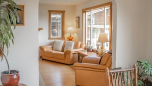 A living room with a sofa, a table with lamps, a potted plant, and a wooden chair. - Tower House  - West Coast Forest Escape (Ucluelet)