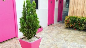 Un edificio con puertas rosadas, una planta en maceta y piso de baldosas.