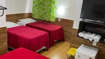 A room with two beds, a TV, a small fridge, and a shower area.