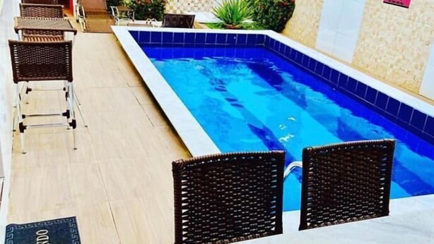 Una piscina con sillones de descanso y un deck de baldosas.