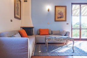 A living room with a sofa, a coffee table, a fireplace, and a large window with a view. - CASA ZOLIA MENDIA, Freshness in the evening, family apartment with view. (Renzano)