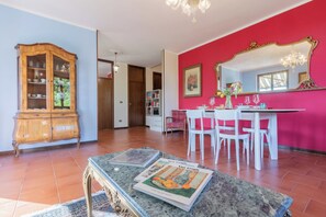 A dining area with a table set for four, a wooden cabinet, and a red wall with a mirror. - CASA ZOLIA MENDIA, Freshness in the evening, family apartment with view. (Renzano)