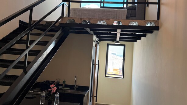A multi-level interior with a staircase, a dining area with chairs and a table, and a window providing a view. - Beautiful loft in Chapultepec (Guadalajara)