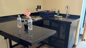 A modern kitchen with a black countertop, a sink, and a dining area with a chair and table. - Beautiful loft in Chapultepec (Guadalajara)