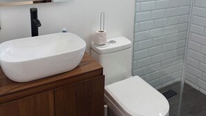 A bathroom with a white sink, toilet, and a glass shower enclosure. - Beautiful loft in Chapultepec (Guadalajara)