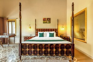 Un lit à baldaquin avec un cadre en bois et une couvre-lit verte, un bureau avec une chaise et un tableau accroché au mur.