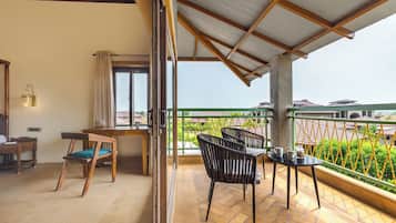 Un balcón con vista a una zona residencial, un escritorio de madera, una silla y una mesa con dos sillas.