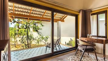 Una habitación con un gran ventanal corredero que da a un espacio exterior con plantas y suelo de baldosas.