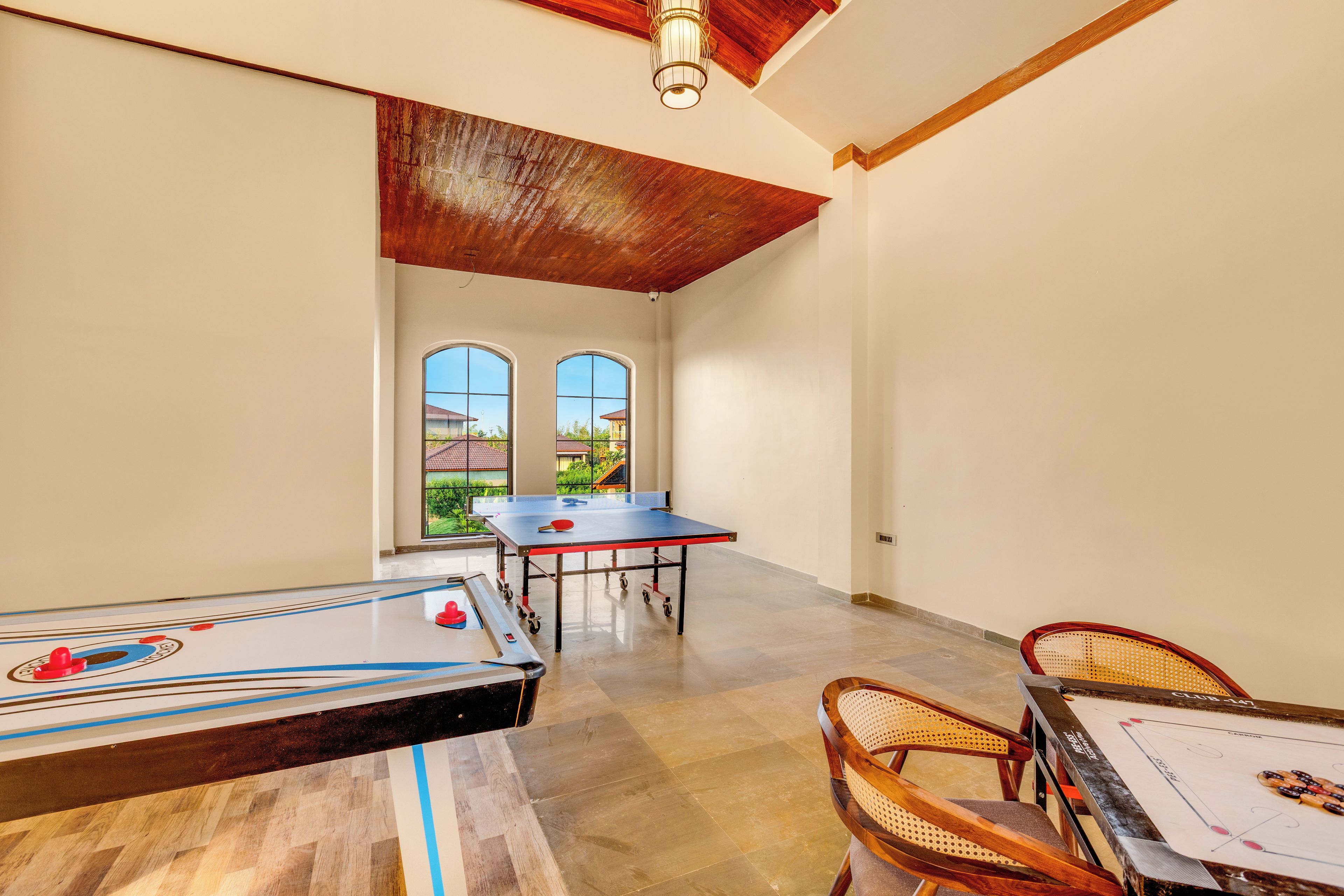 Una habitación amplia con mesa de ping pong, mesa de futbolín y mesa de billar.