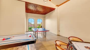 Una habitación amplia con mesa de ping pong, mesa de futbolín y mesa de billar.