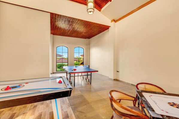 Une pièce spacieuse équipée d’une table de ping-pong, d’un baby-foot et d’une table de billard.