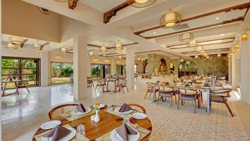 Un comedor amplio con varias mesas, sillas y un ventanal que ofrece vistas al exterior.